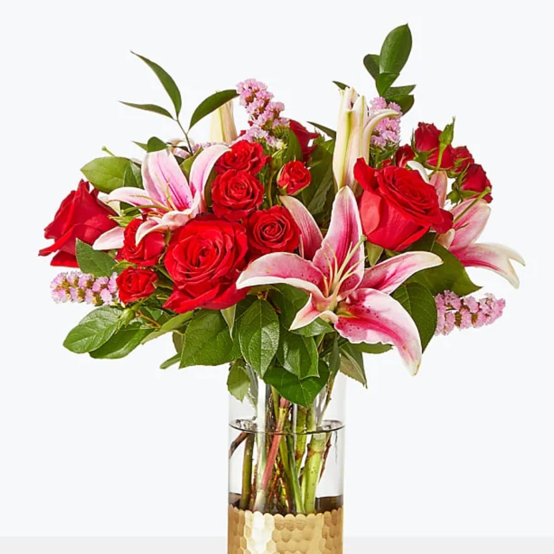 Bouquet of red roses and pink lilies in a clear glass vase