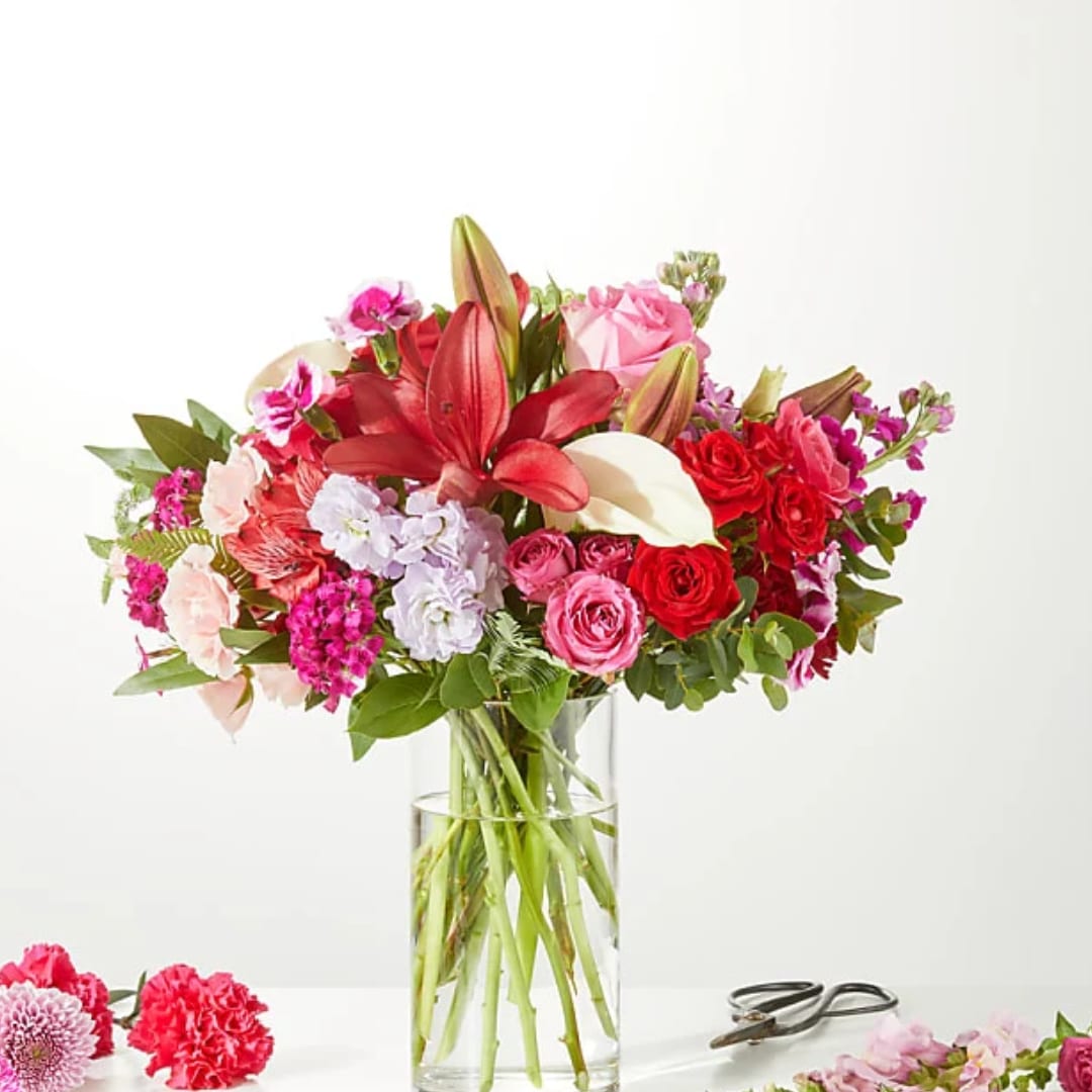 Mixed bouquet of red, pink, and white flowers in a clear glass vase