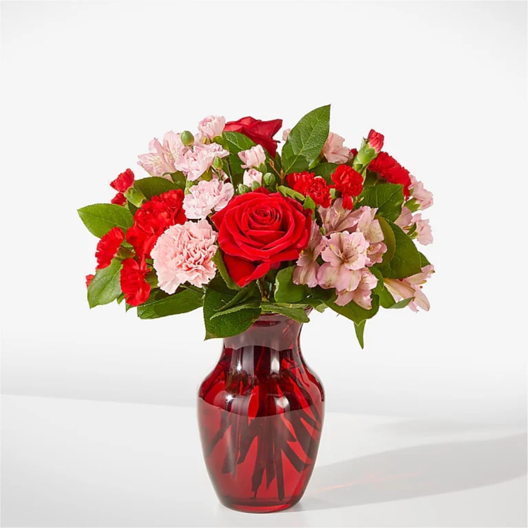Red roses and pink carnations in a red glass vase