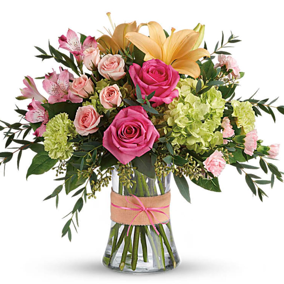Pink and peach roses with lilies and green hydrangeas in a glass vase