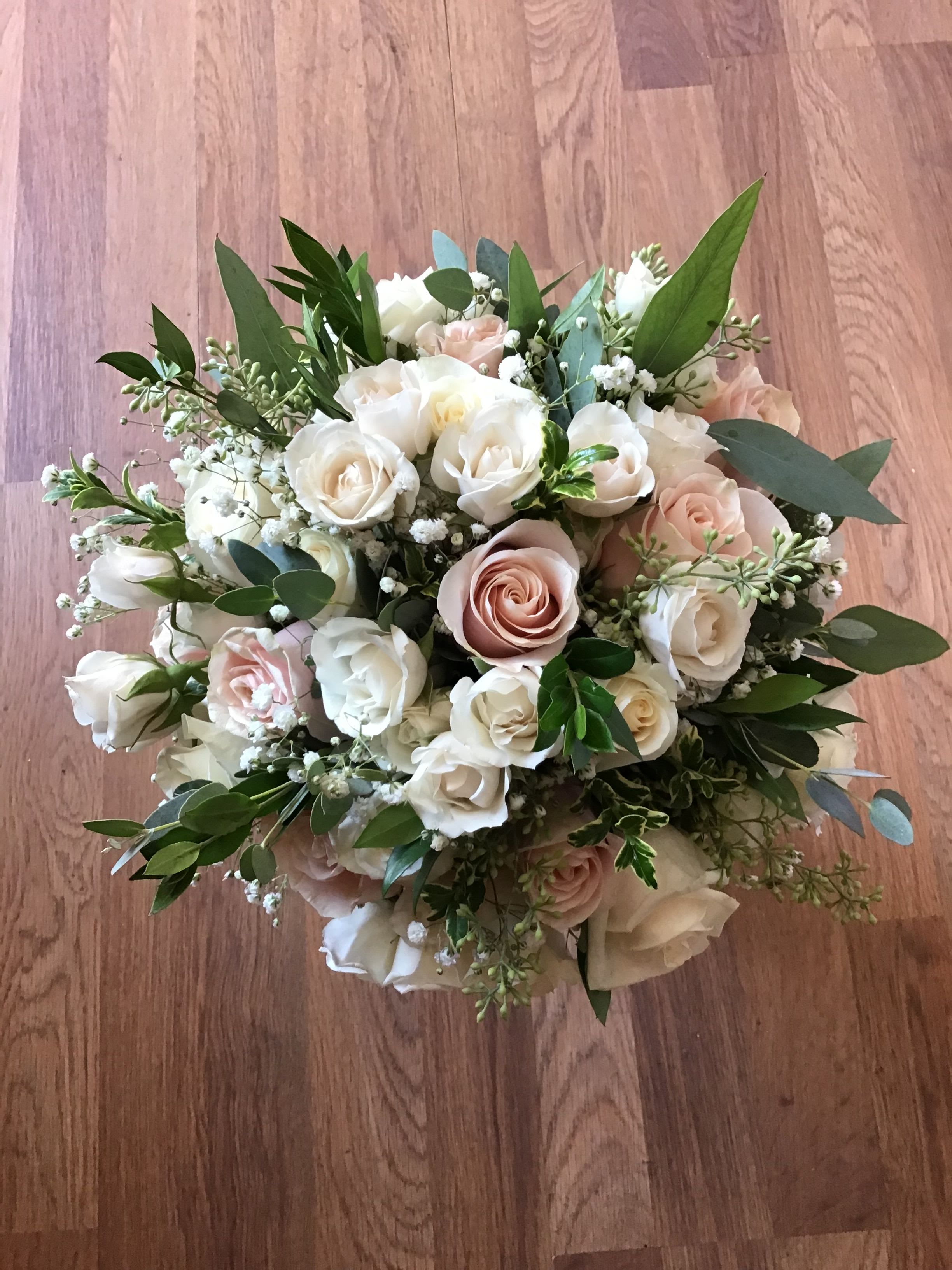 Blushing Beauty Bouquet - A delicate mix of blush and white roses accented with fresh greenery creates a soft, elegant bouquet perfect for anniversaries and weddings.