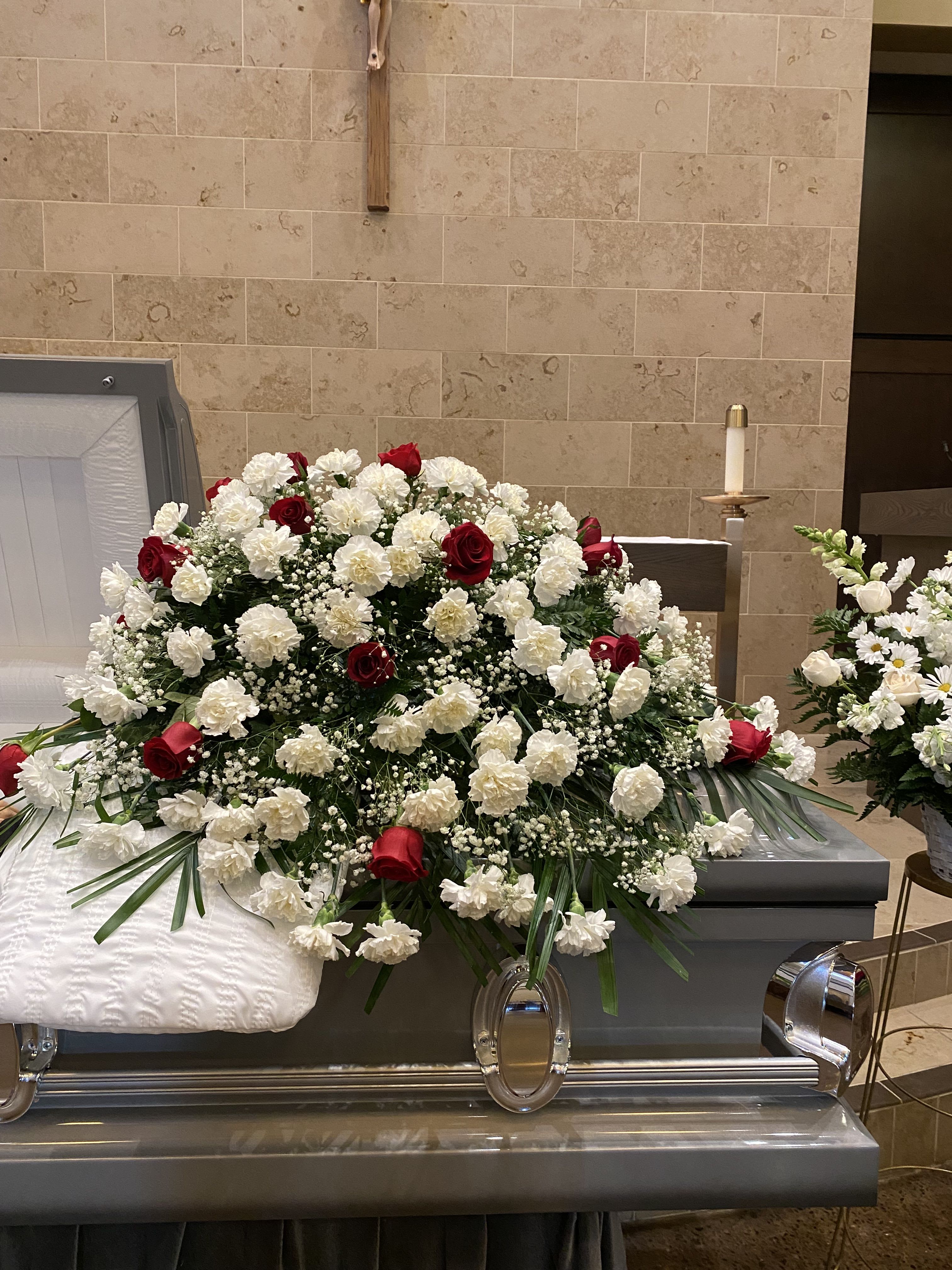 Sympathy Casket Spray Carnations and Roses - A beautiful casket spray with carnations and roses accompanied by greenery.   If you would like one of the available colors below for the roses only, please specify your preference in the Special Instructions section when placing your order, if not then the order will be made with red roses. Color requests are subject to availability.  Available Colors:  1)Pink 2)Yellow 3)Off-White 4)Fuchsia