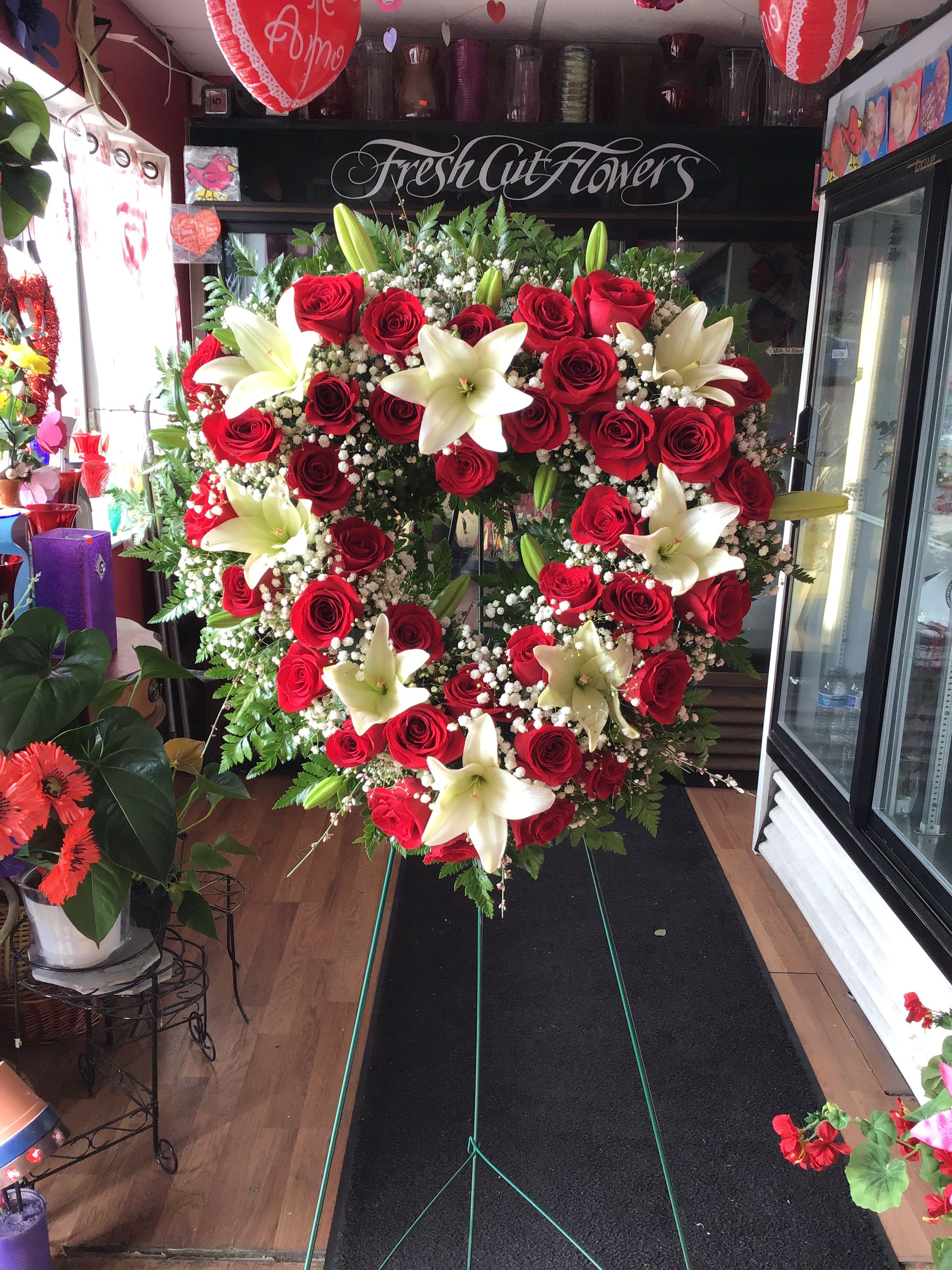 Heartfelt Tribute Standing Spray - Beautiful sympathy heart with roses and lilies accompanied by greenery.  If you would like one of the available colors below for the roses, please specify your preference in the Special Instructions section when placing your order, if not then the order will be made with red roses. Color requests are subject to availability.  Available Colors:  1)Pink 2)Yellow 3)Off-White 4)Fuchsia