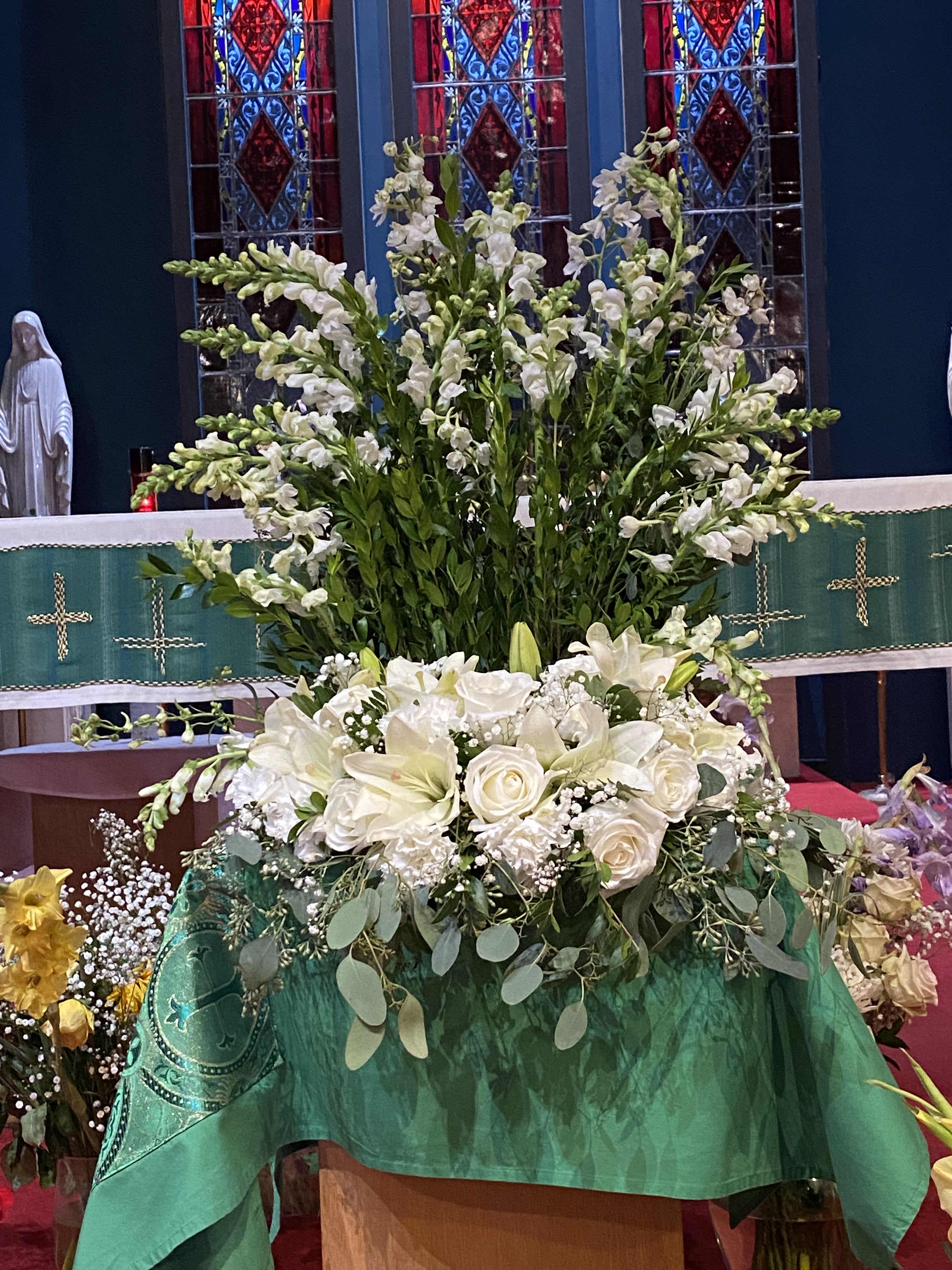 Heavenly Grace Urn Arrangement - This beautiful arrangement is a graceful tribute that honors a life beautifully lived. Featuring an elegant design of pristine white blooms complemented by lush greenery, this standing arrangement offers a heartfelt expression of sympathy, comfort, and everlasting love.