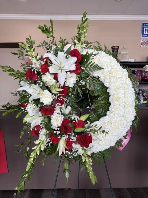 Sympathy Wreath Half and Half - The beautiful Wreath is a graceful expression of remembrance, symbolizing the enduring bond shared with a loved one. Thoughtfully designed with a beautiful balance of fresh blooms and lush greenery, this elegant standing wreath offers comfort, peace, and heartfelt sympathy. Displayed on a wire easel, it serves as a timeless tribute to a life that will always be remembered.