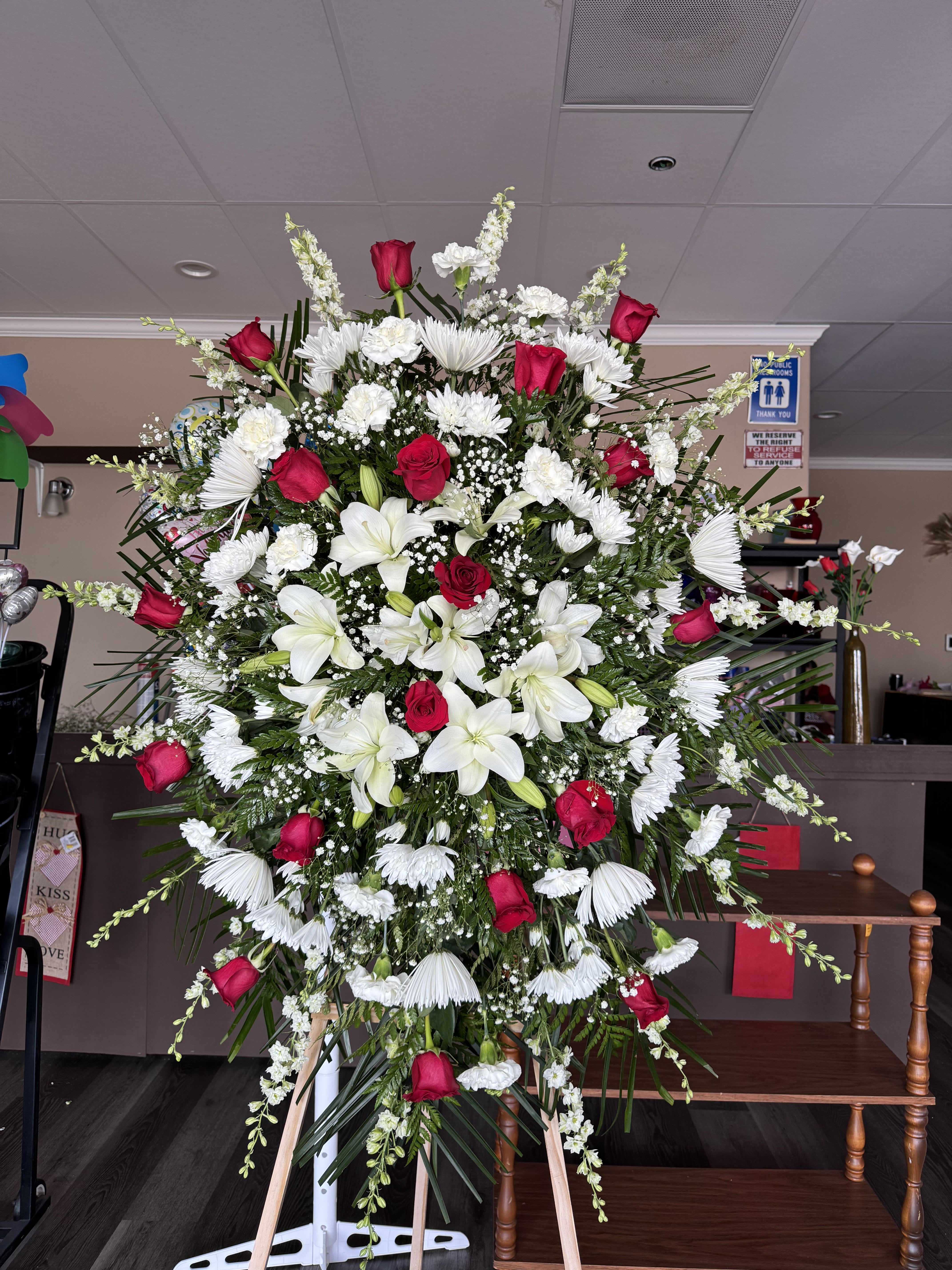 Peaceful Memories - The Peaceful Memories Standing Spray offers a beautiful way to celebrate a life filled with love and treasured memories. An elegant blend of fresh blooms and lush greenery.  If you would like one of the available colors below for the roses only, please specify your preference in the Special Instructions section when placing your order, if not then the order will be made with red roses. Color requests are subject to availability.  Available Colors:  1)Pink 2)Yellow 3)Off-White 4)Fuchsia