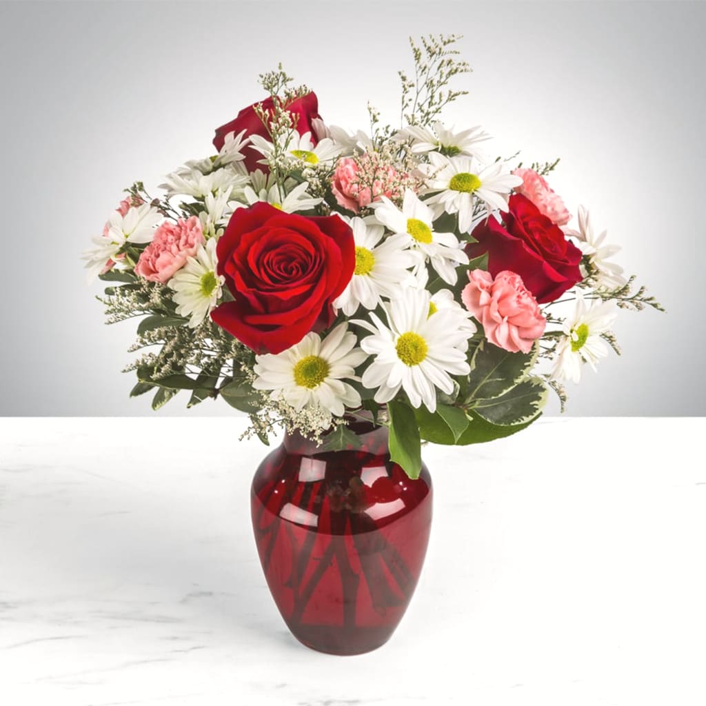 Red roses and white daisies in a red glass vase