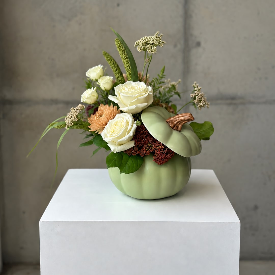 Pumpkin-shaped vase with white roses and autumn flowers