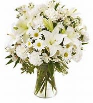 Bouquet of white lilies, daisies, and carnations in a clear glass vase