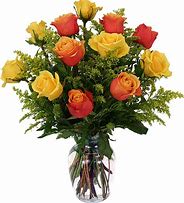 Yellow and orange roses arranged in a clear glass vase with filler accents