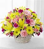Yellow lilies and daisies with pink carnations in a white wicker basket