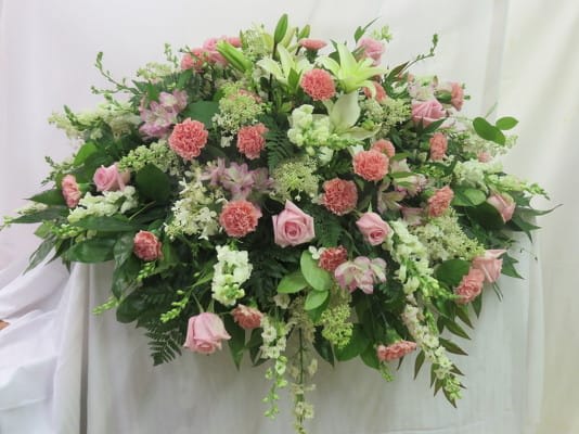 Large horizontal spray of pink roses and carnations with white lilies and other white flowers