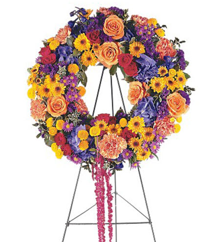 Colorful standing wreath of roses, carnations, and daisies on a metal easel stand