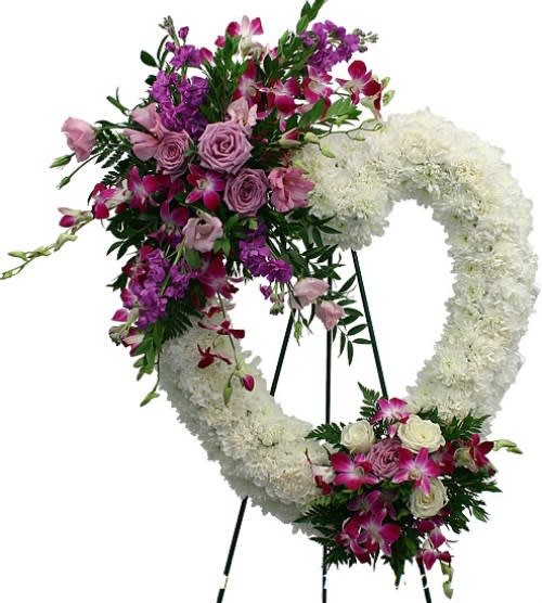 Heart-shaped white sympathy wreath with purple and pink flowers on a standing easel