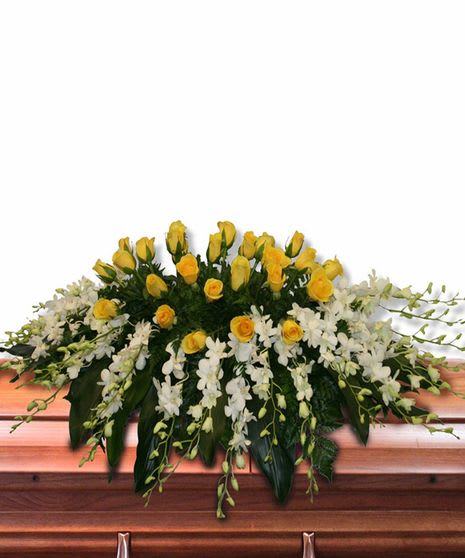 Yellow rose and white orchid casket spray arranged across a wooden casket