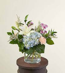 Mixed bouquet in a clear glass vase with white lily and blue hydrangea