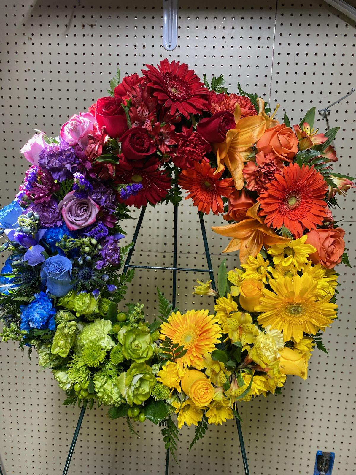 Rainbow heart-shaped floral wreath on a metal stand