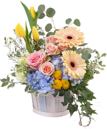 Mixed bouquet in a wooden basket with yellow tulips, pink roses, and gerbera daisies