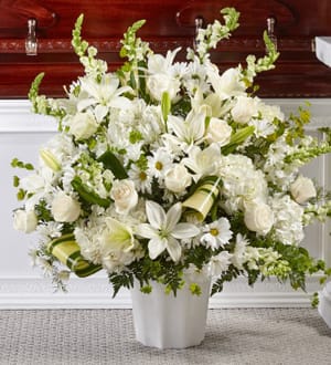 White floral arrangement in a white vase with lilies and roses