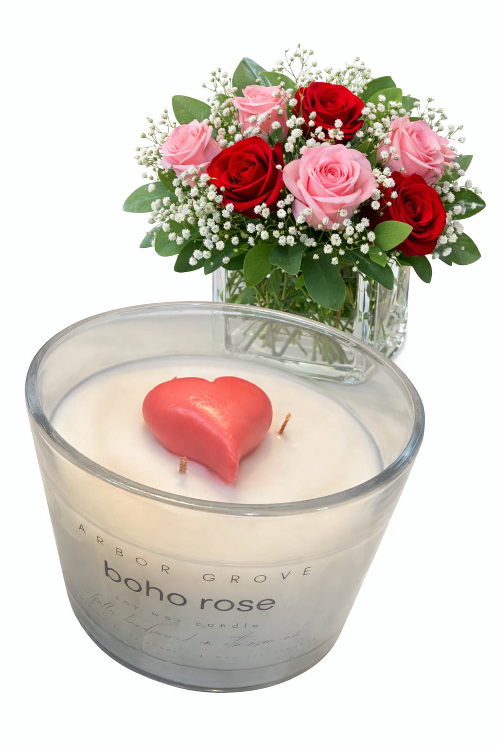 Pink and red roses in a glass vase beside a heart-shaped candle