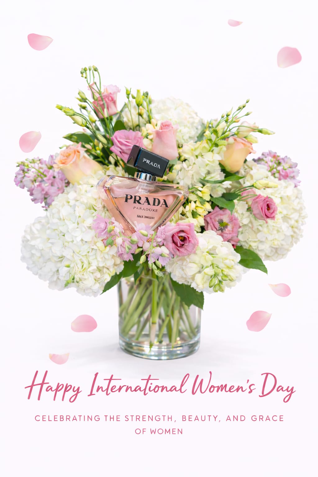 Pink and white flower arrangement in a glass vase with a Prada perfume bottle