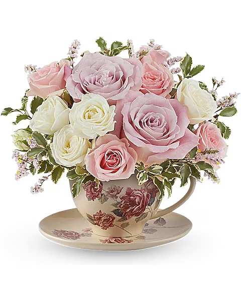 Pink and white roses arranged in a floral teacup with saucer