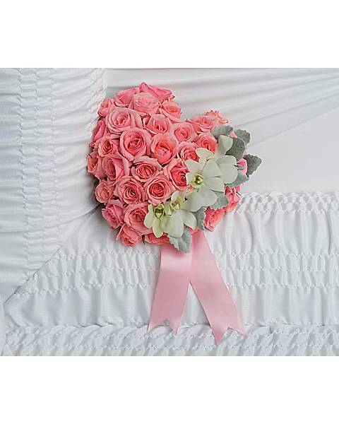 Pink rose bouquet with pale flowers and a pink ribbon on white bedding