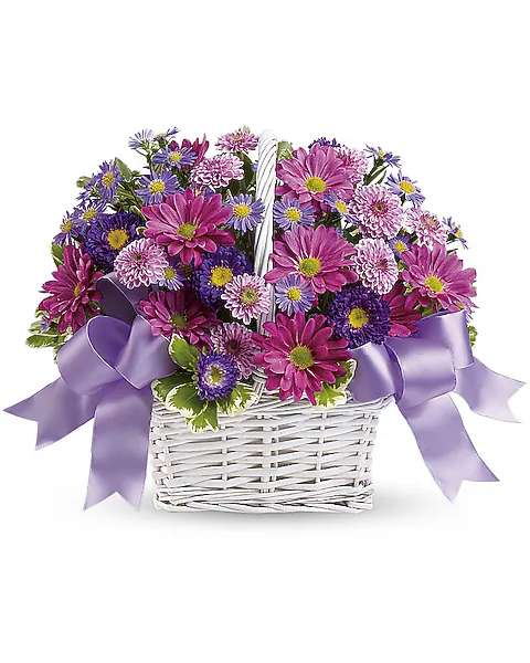 Purple and pink mixed flowers in a white wicker basket with lavender ribbon