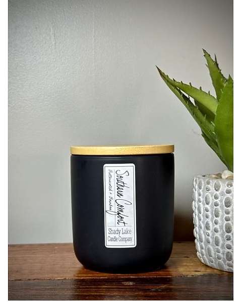 Black candle jar with a gold lid beside a small potted succulent