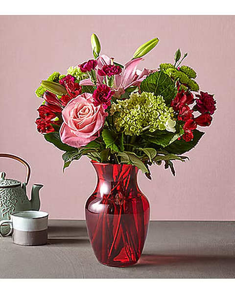 Pink and red flower arrangement in a red glass vase