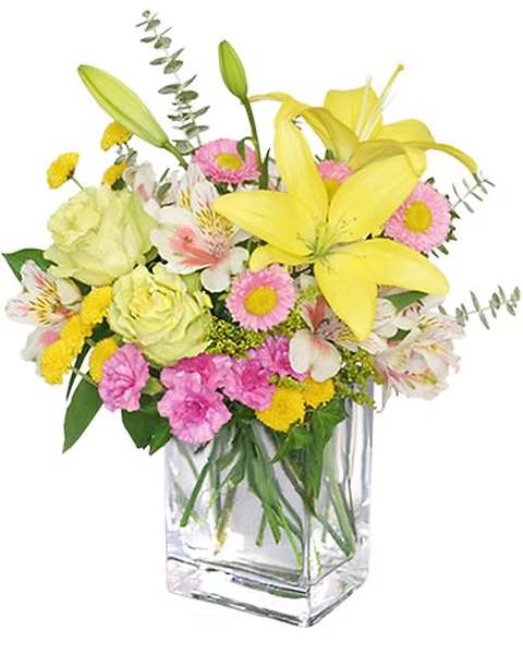Mixed bouquet of yellow lilies, pink daisies, and white flowers in a glass vase