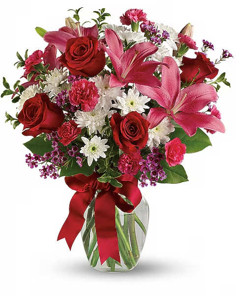Bouquet of red roses, pink lilies, and white daisies in a glass vase