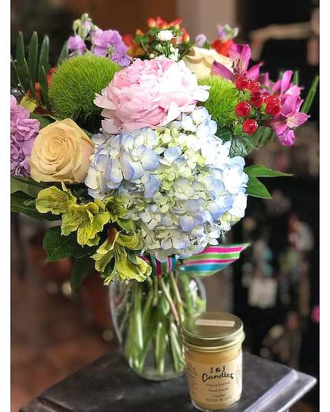 Mixed bouquet in a glass vase with a candle beside it