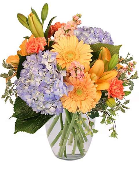Mixed bouquet of orange and lavender flowers in a clear glass vase