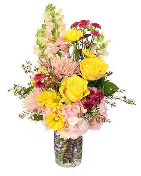 Mixed bouquet of yellow roses, pink blooms, and snapdragons in a glass vase