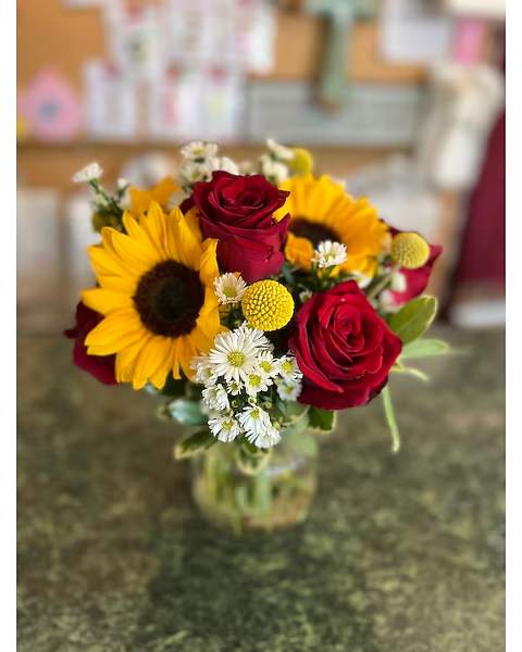 Bouquet of red roses and sunflowers in a glass vase