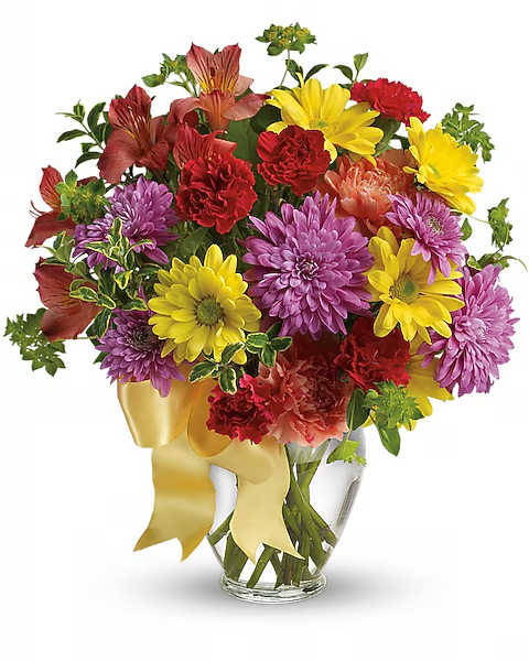 Mixed bouquet of yellow, purple, and red flowers in a glass vase with a yellow ribbon