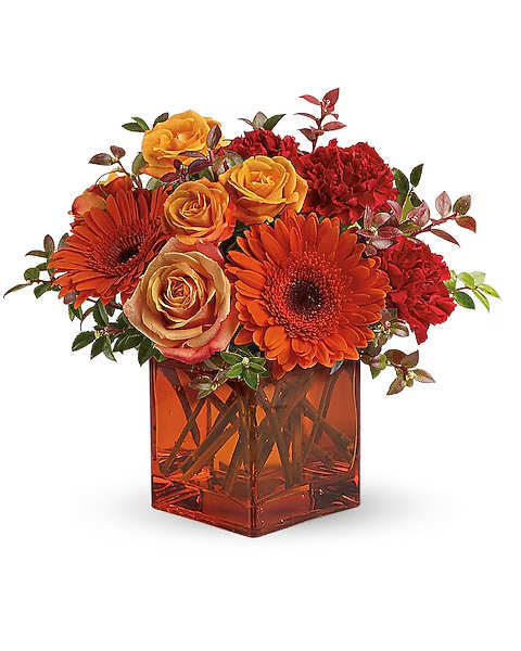 Orange and red flowers arranged in a square amber vase
