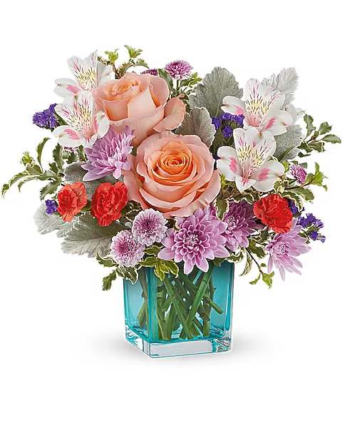 Bouquet of peach roses, white alstroemeria, and purple flowers in a blue glass vase