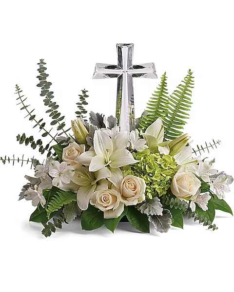 White lilies and cream roses arranged around a silver cross