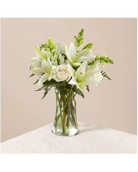 White lilies and roses arranged in a clear glass vase