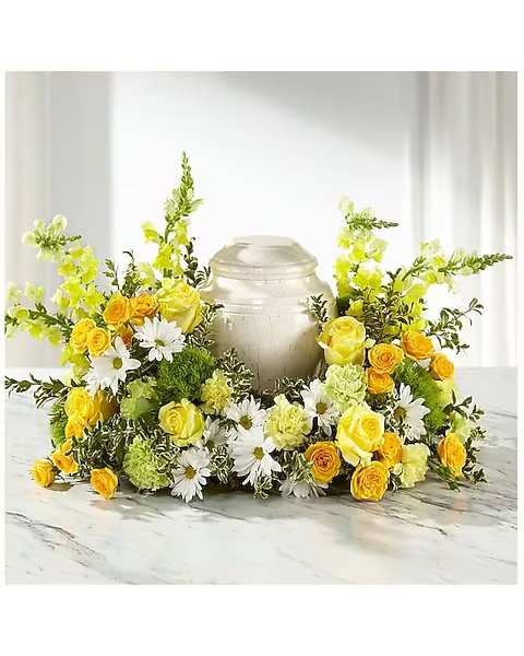Yellow roses and white daisies arranged around a silver urn