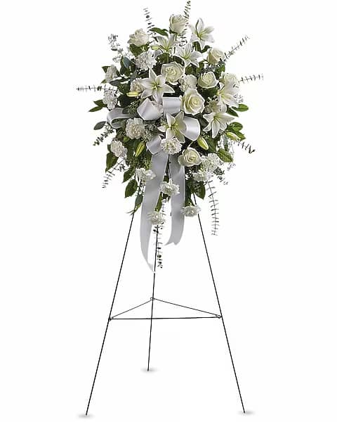 White floral standing spray with roses and lilies on an easel