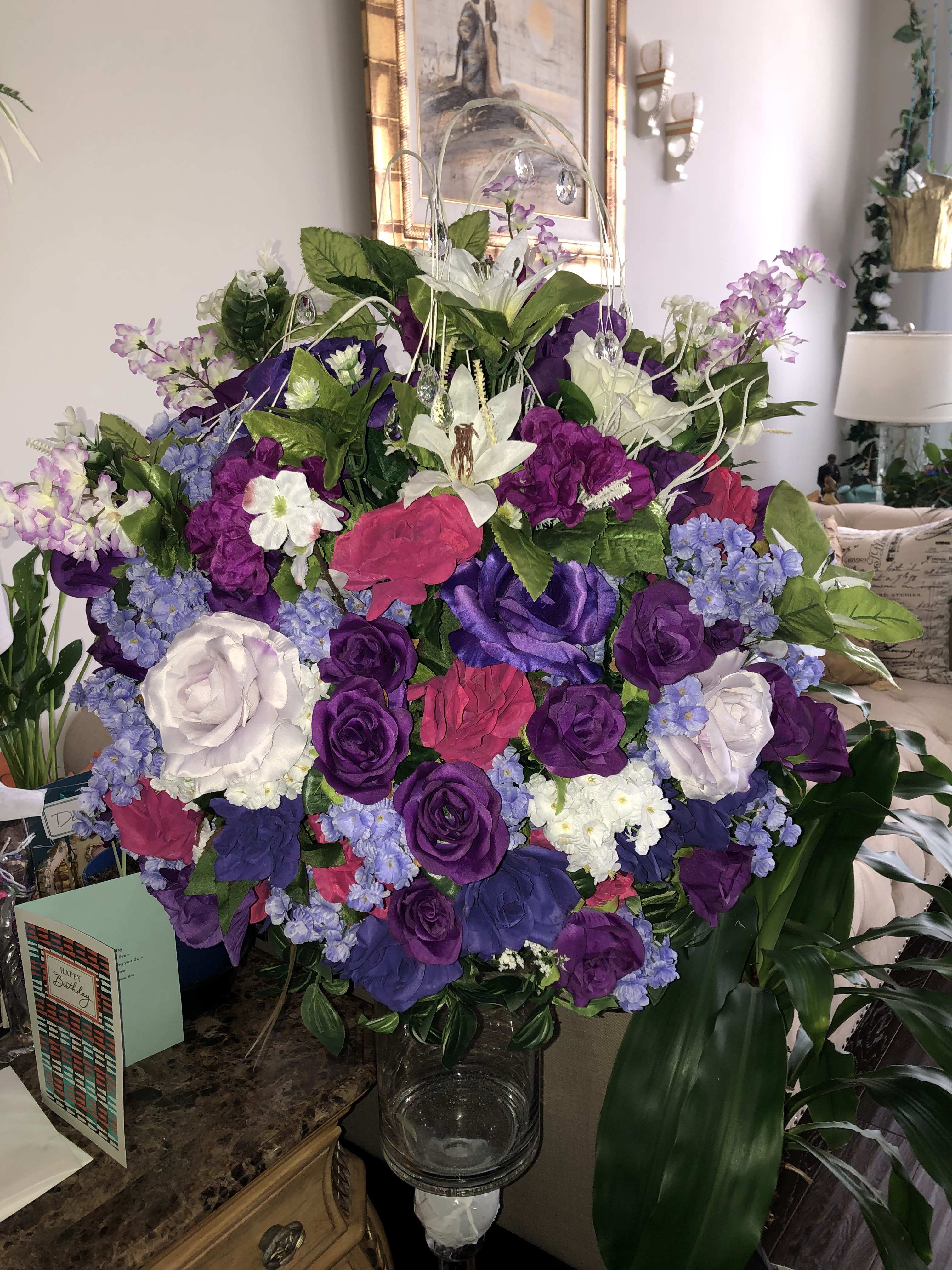 Large bouquet of purple, pink, white, and blue flowers in a glass vase