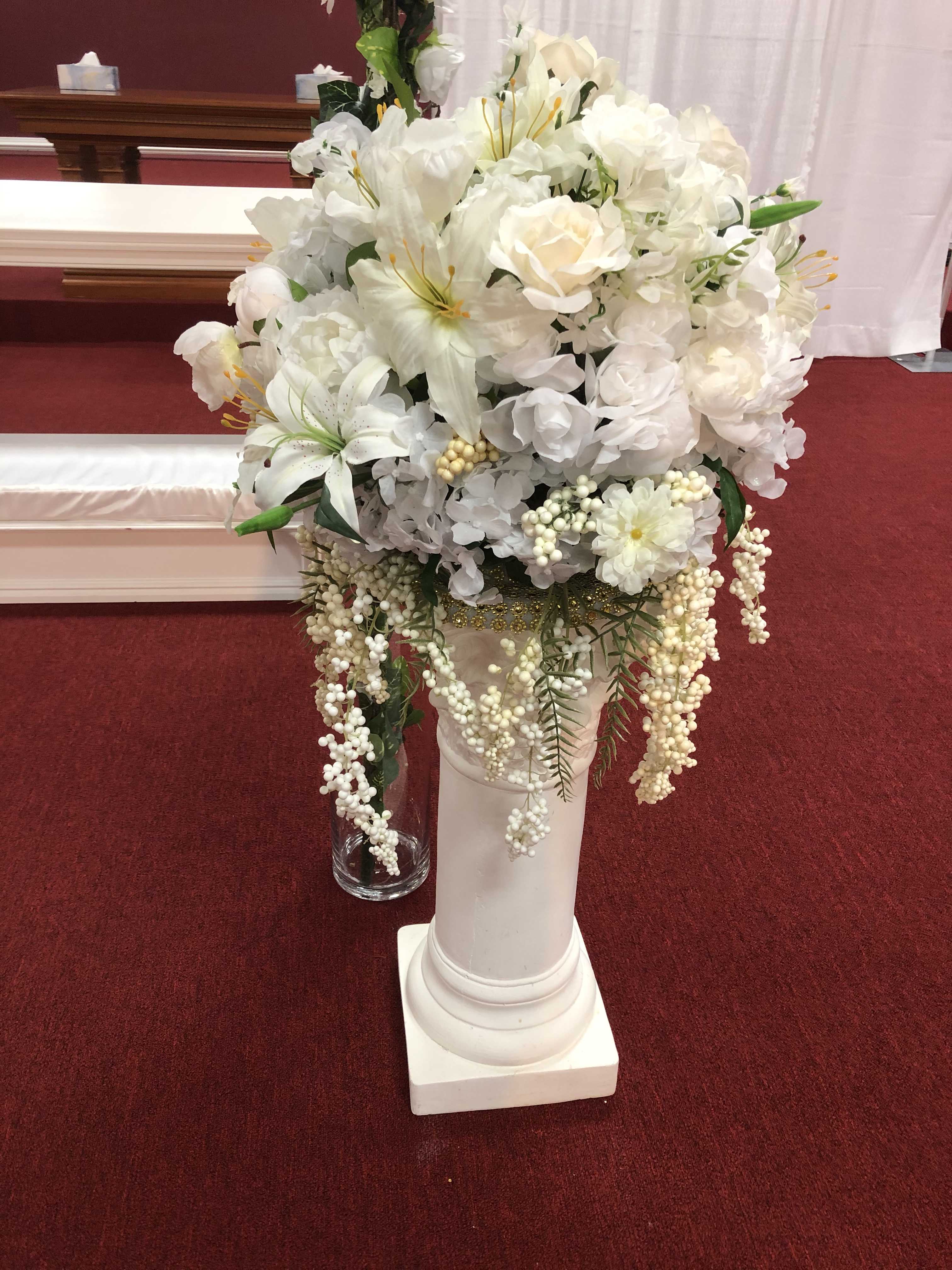 White floral arrangement in a tall pedestal vase