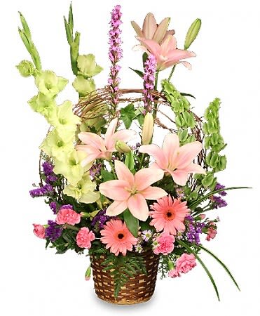 Basket Of Memories - This arrangement is an elegant tribute to the favorite times and the favorite people in our lives. As our best memories stand out in our minds, these stunning flowers definitely capture your attention, with pink lilies, gerbera daisies, gladiolus, bells of Ireland and purple accent flowers. A grapevine handle brings this arrangement full-circle as a visual collection of memories.  Includes Brown Wicker Basket With Liner, Grapevine (Fashioned Into A Faux Handle), Foliage: Leather Leaf, Sprengeri, Seeded Eucalyptus, Variegated Pittosporum, Ivy, Liriope, Green Gladiolus, Bells Of Ireland, Pale Pink Lilies, Pink Gerberas, Purple Liatris, Pink Mini Carnations, Pink Aster (Monte Casino), Purple Statice.
