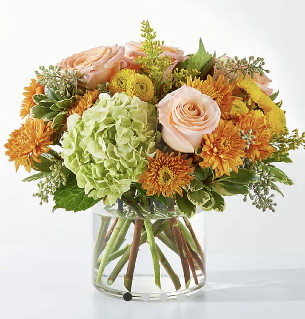 Peach roses and orange mums in a clear glass vase