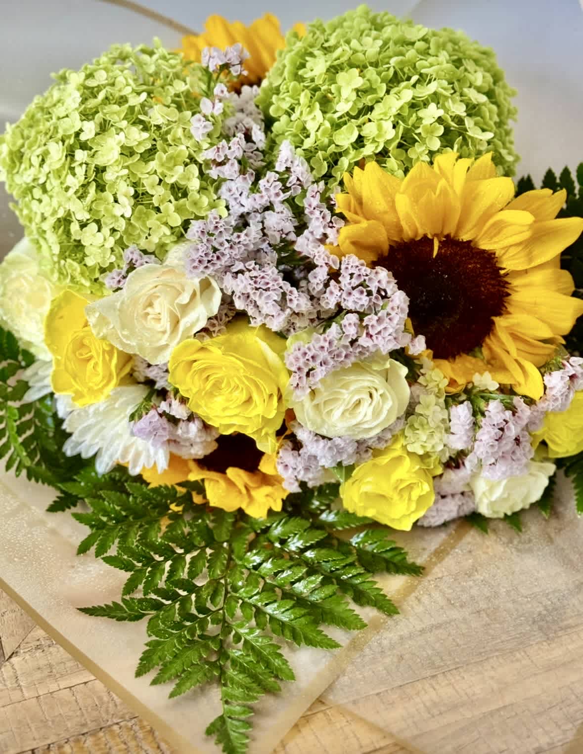 Bouquet of yellow sunflowers, cream roses, and green hydrangeas