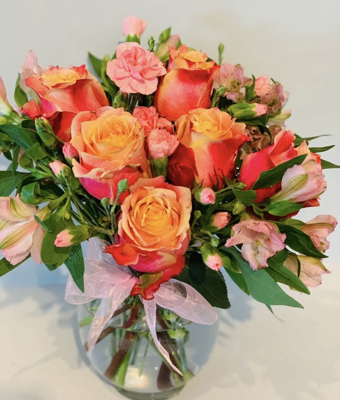 Bouquet of orange and pink roses with alstroemeria in a glass vase
