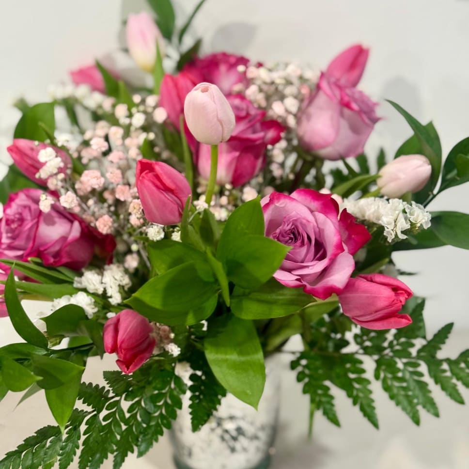 Pink roses and tulips arranged in a clear vase